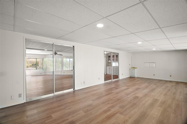 spare room featuring baseboards, wood finished floors, a drop ceiling, and a ceiling fan