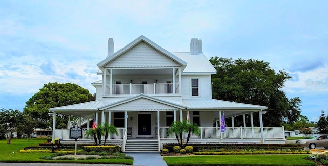 view of front of house featuring covered porch, a balcony, metal roof, and a chimney
