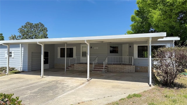 view of front of property featuring a porch, concrete driveway, and a carport