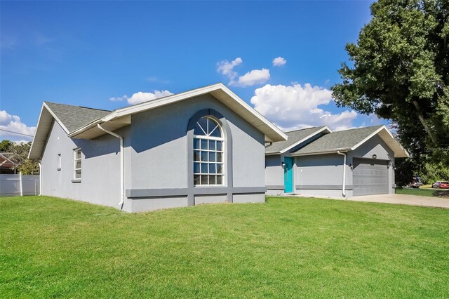 ranch-style house with an attached garage, concrete driveway, a front yard, stucco siding, and a shingled roof