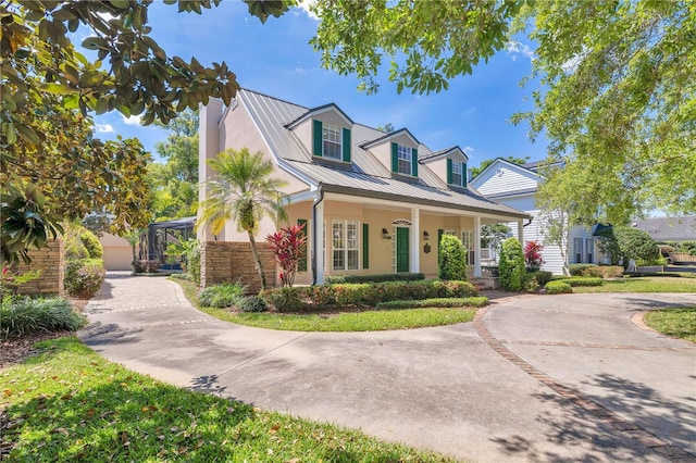 1560 Woodland Ave, Winter Park, FL 32789 - cape cod-style house with metal roof, a standing seam roof, stucco siding, curved driveway, and a porch