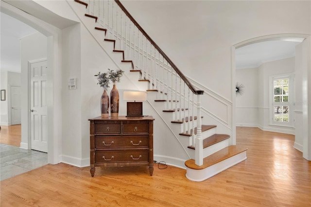 1560 Woodland Ave, Winter Park, FL 32789 - staircase featuring crown molding, baseboards, wood finished floors, and arched walkways