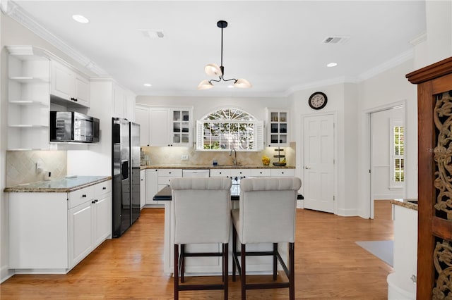 1560 Woodland Ave, Winter Park, FL 32789 - kitchen with visible vents, white cabinets, stainless steel fridge, and open shelves
