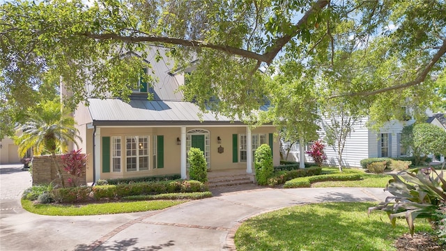 1560 Woodland Ave, Winter Park, FL 32789 - view of front of property featuring metal roof, driveway, a front lawn, stucco siding, and covered porch