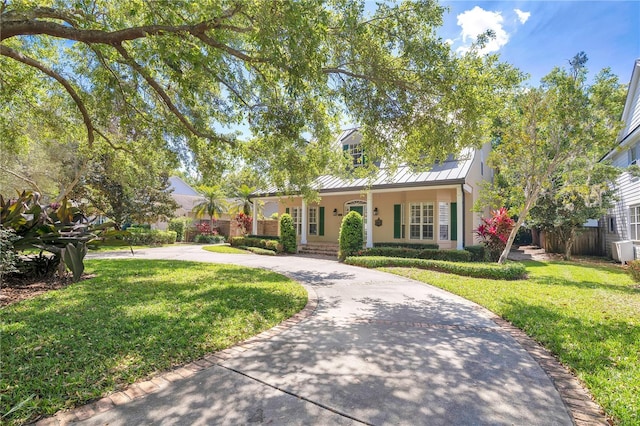 1560 Woodland Ave, Winter Park, FL 32789 - view of front facade with metal roof, a standing seam roof, a front lawn, covered porch, and curved driveway
