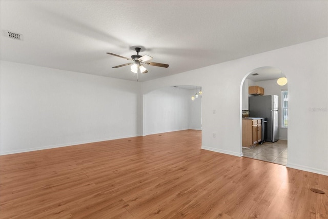 2741 Merrieweather Ln, Kissimmee, FL 34743 - unfurnished room featuring light wood-style floors, baseboards, visible vents, arched walkways, and ceiling fan