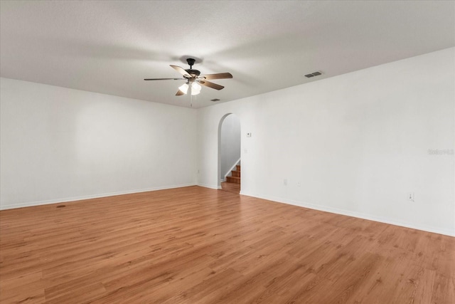 2741 Merrieweather Ln, Kissimmee, FL 34743 - empty room featuring baseboards, arched walkways, ceiling fan, light wood-style flooring, and visible vents