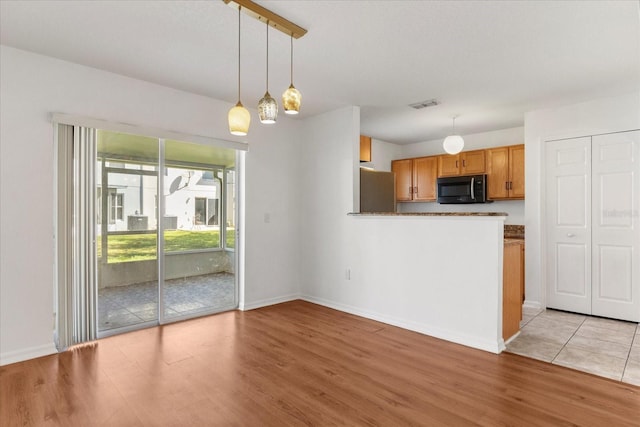 2741 Merrieweather Ln, Kissimmee, FL 34743 - kitchen featuring light wood finished floors, visible vents, decorative light fixtures, and freestanding refrigerator