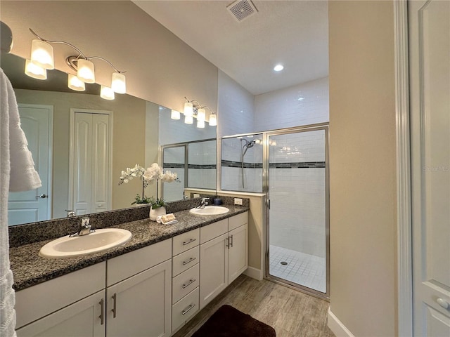 bathroom with a shower stall, wood finished floors, visible vents, and a sink