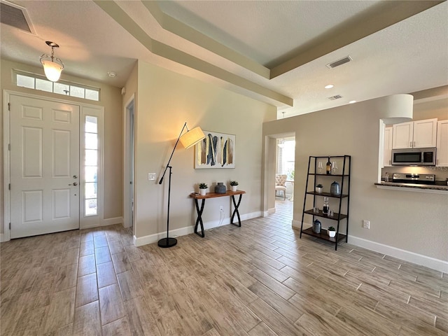 foyer entrance with light wood-style floors, visible vents, and baseboards
