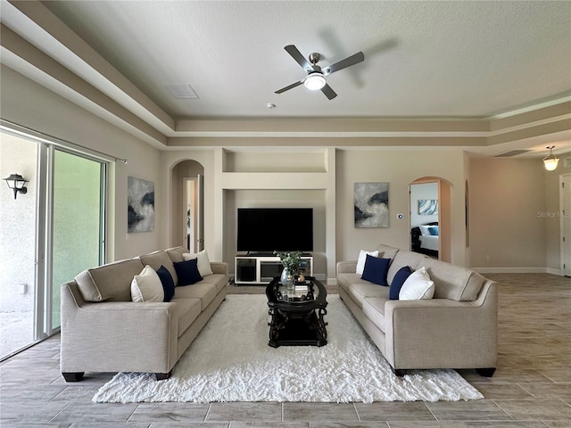 living room with arched walkways, wood tiled floor, visible vents, and ceiling fan