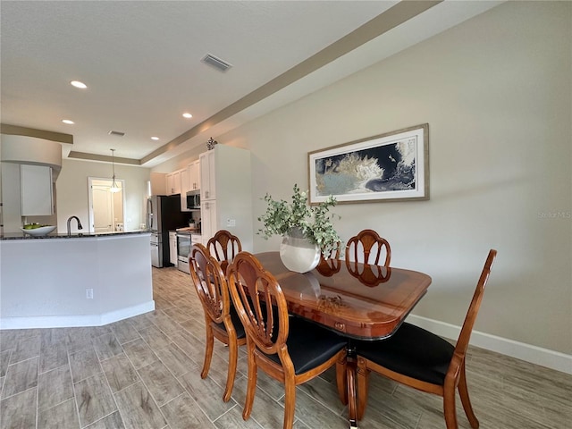 dining room with light wood finished floors, baseboards, visible vents, and recessed lighting