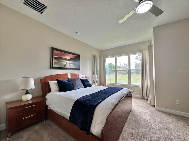 carpeted bedroom with a textured ceiling, visible vents, baseboards, and ceiling fan
