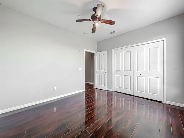 unfurnished bedroom featuring visible vents, a closet, baseboards, wood finished floors, and a ceiling fan