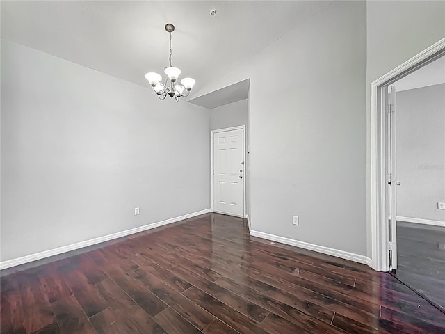 spare room with an inviting chandelier, wood finished floors, and baseboards