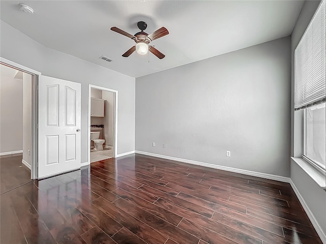 unfurnished bedroom featuring connected bathroom, a ceiling fan, visible vents, baseboards, and wood finished floors
