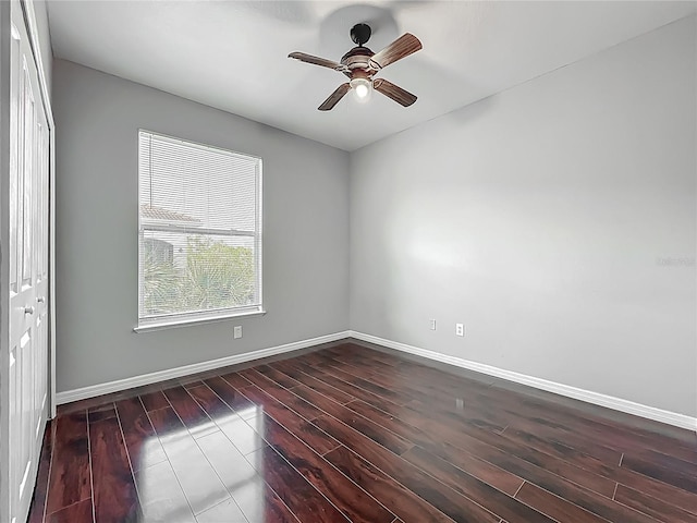 unfurnished room featuring a ceiling fan, dark wood finished floors, and baseboards