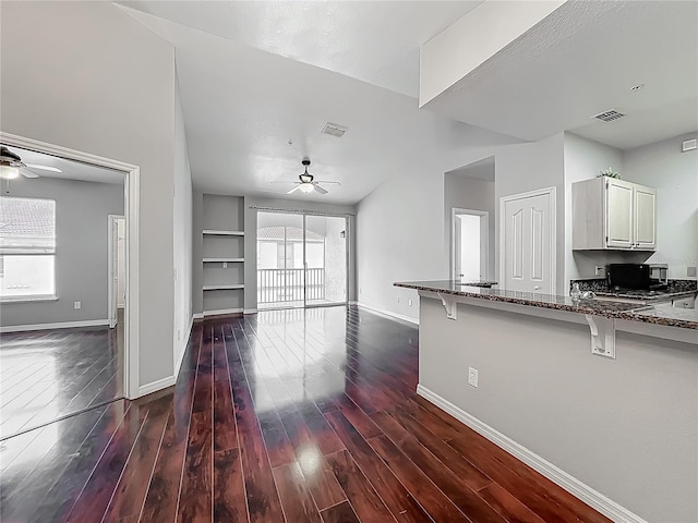 unfurnished living room with ceiling fan, visible vents, and baseboards