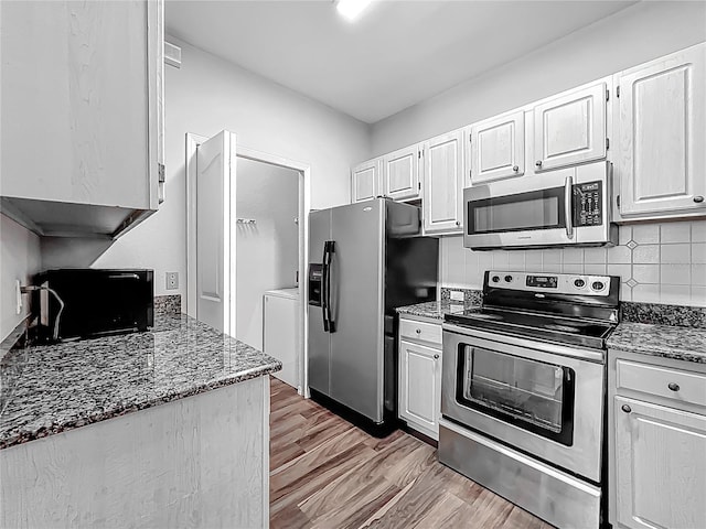 kitchen with tasteful backsplash, dark stone counters, light wood-style floors, appliances with stainless steel finishes, and washer / clothes dryer