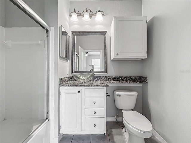 full bathroom with combined bath / shower with glass door, baseboards, toilet, tile patterned floors, and vanity