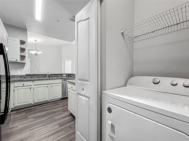 washroom with wood finished floors, laundry area, washer / dryer, a textured wall, and a sink