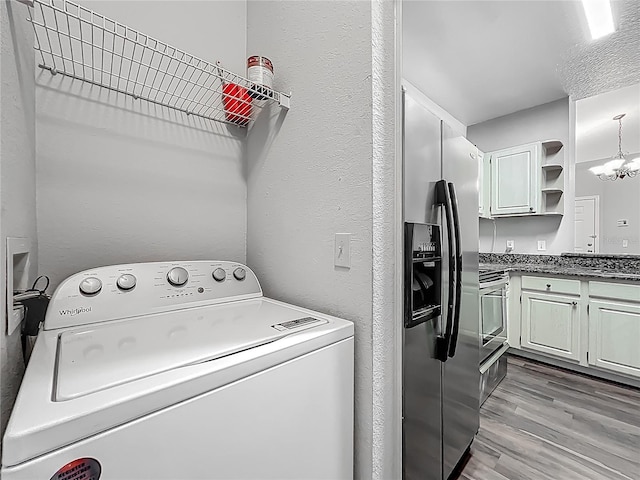 washroom featuring a chandelier, laundry area, a textured wall, light wood-style flooring, and washer / clothes dryer