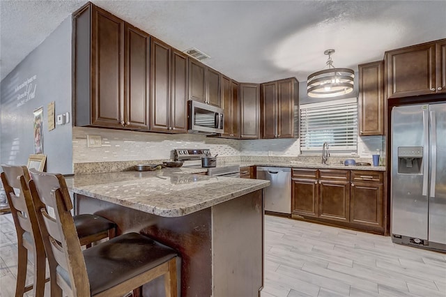 243 W Martin St, Apopka, FL 32712 - kitchen with a peninsula, light stone counters, visible vents, and stainless steel appliances