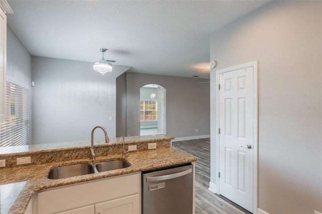 1197 Tallow Rd, Apopka, FL 32703 - kitchen with stainless steel dishwasher, a sink, light wood-style floors, arched walkways, and white cabinets