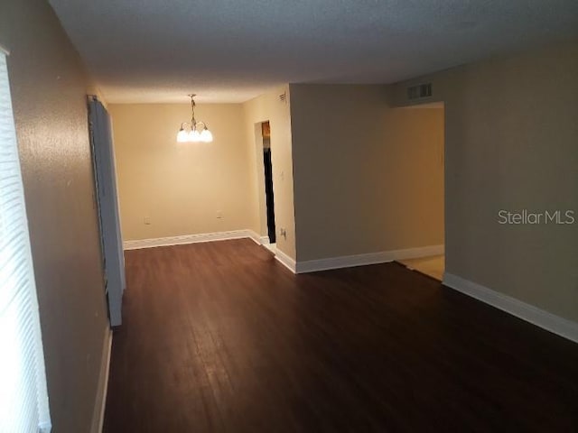4779 S Texas Ave Unit 4779C, Orlando, FL 32839 - unfurnished room featuring an inviting chandelier, dark wood-type flooring, baseboards, and visible vents