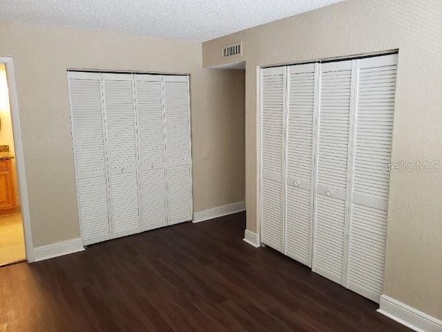 4779 S Texas Ave Unit 4779C, Orlando, FL 32839 - unfurnished bedroom with a textured ceiling, dark wood-style floors, multiple closets, baseboards, and visible vents
