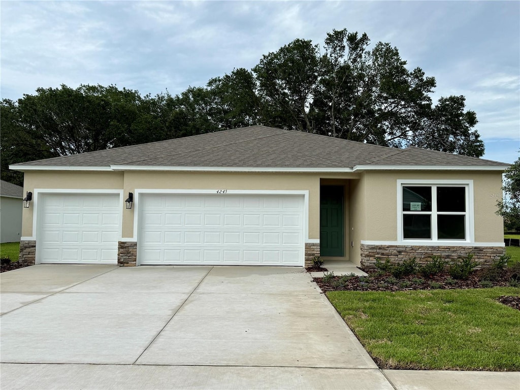 4245 Acoma Dr, Ormond Beach, FL 32174 - view of front facade with stone siding, stucco siding, driveway, an attached garage, and a front yard