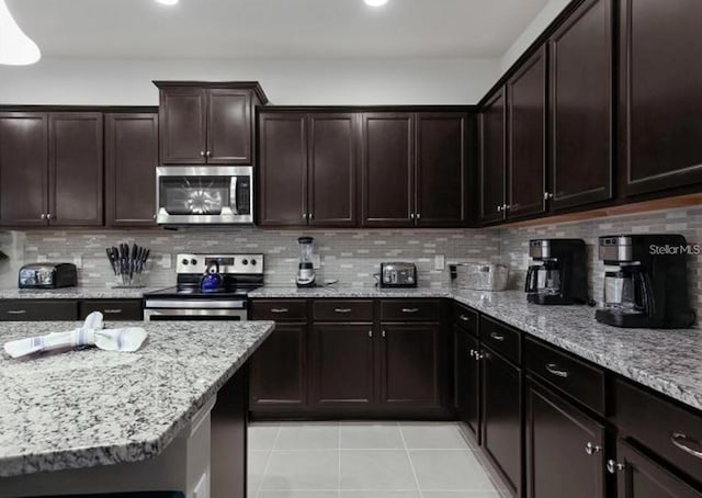 8892 Bengal Ct, Kissimmee, FL 34747 - kitchen featuring appliances with stainless steel finishes, light tile patterned floors, light stone countertops, and tasteful backsplash