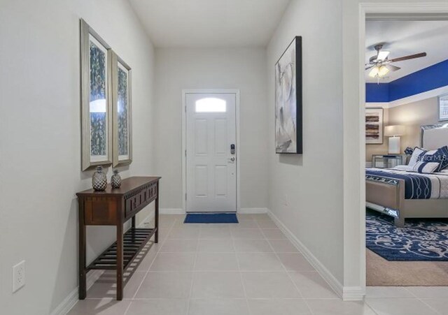 8892 Bengal Ct, Kissimmee, FL 34747 - entryway featuring light tile patterned flooring, ceiling fan, baseboards, and light carpet