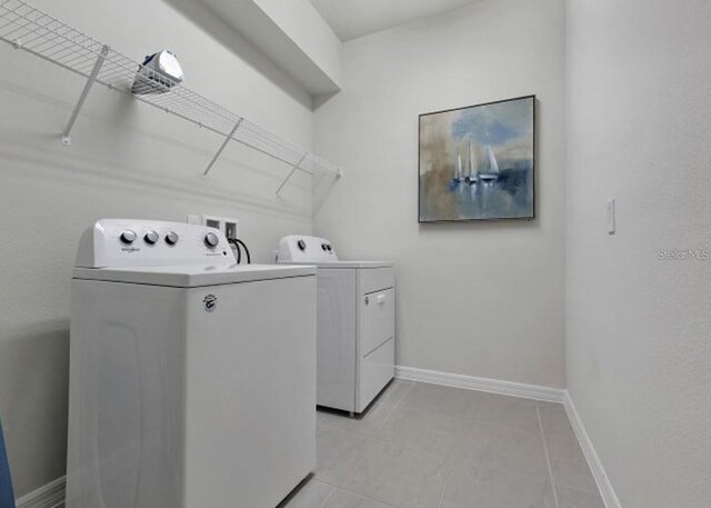 8892 Bengal Ct, Kissimmee, FL 34747 - laundry area featuring washer and clothes dryer, baseboards, and light tile patterned flooring