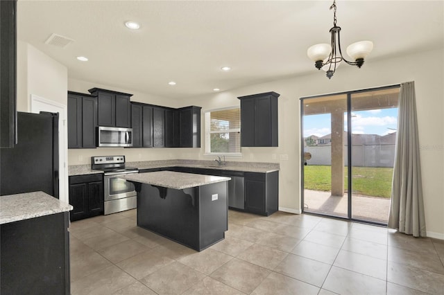 2200 Rapollo Dr, Kissimmee, FL 34741 - kitchen with a sink, a kitchen island, dark cabinetry, appliances with stainless steel finishes, and visible vents