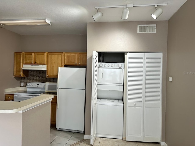 9021 Lee Vista Blvd Unit 1707, Orlando, FL 32829 - kitchen featuring white appliances, under cabinet range hood, decorative backsplash, stacked washer and dryer, and visible vents