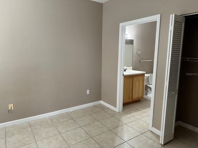 9021 Lee Vista Blvd Unit 1707, Orlando, FL 32829 - unfurnished bedroom with light tile patterned flooring, baseboards, a closet, and connected bathroom