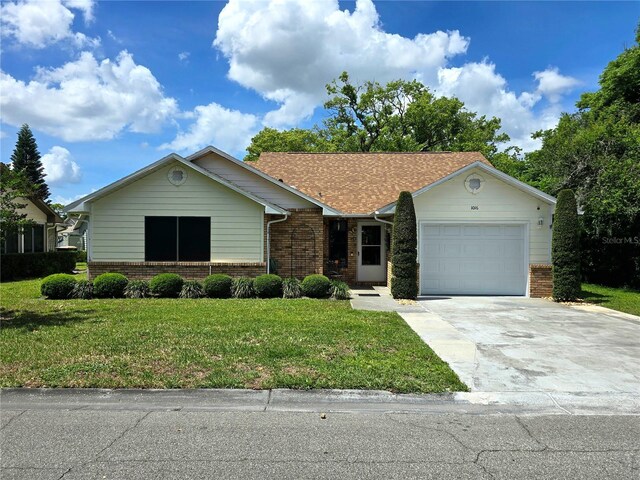 ranch-style home featuring a front lawn, driveway, an attached garage, and brick siding