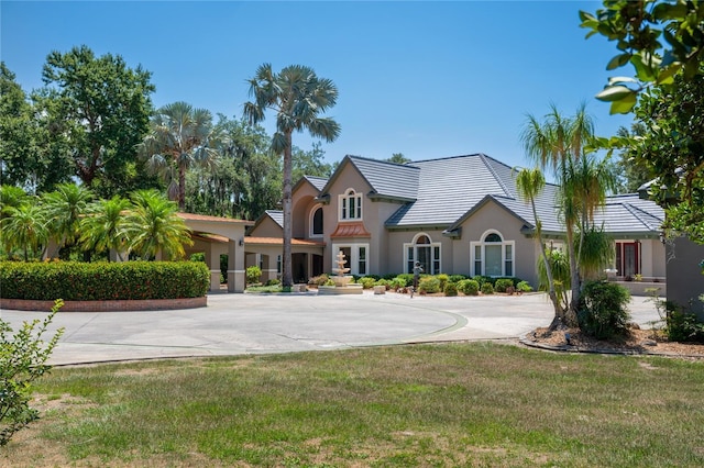 11450 Nellie Oaks Bnd, Clermont, FL 34711 - view of front of home featuring stucco siding, curved driveway, a front lawn, and a tiled roof