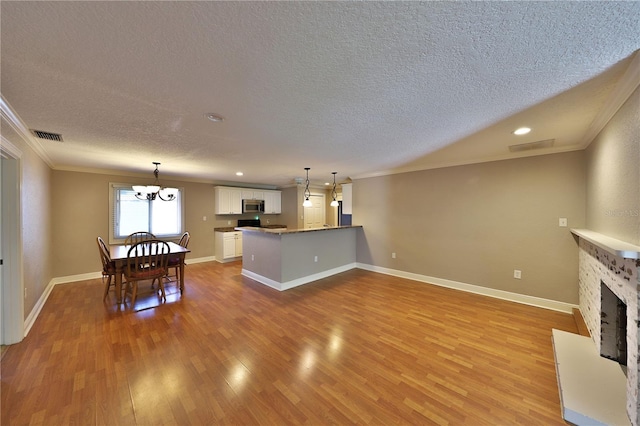 426 S Lakemont Ave, Winter Park, FL 32792 - kitchen with white cabinetry, light wood-type flooring, stainless steel microwave, a fireplace with raised hearth, and a peninsula