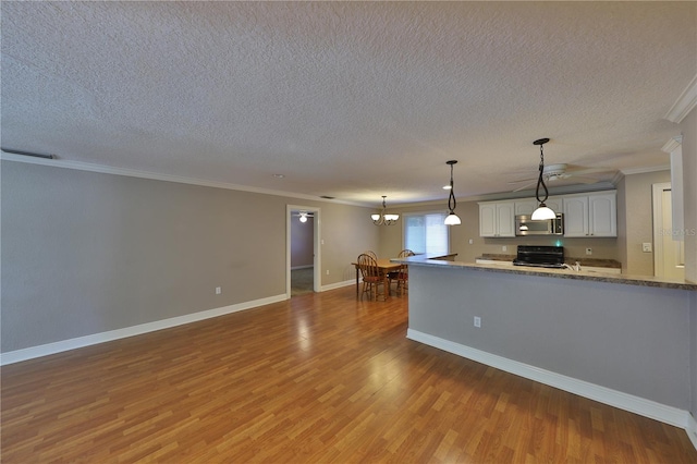 426 S Lakemont Ave, Winter Park, FL 32792 - kitchen with a notable chandelier, wood finished floors, stove, stainless steel microwave, and white cabinets