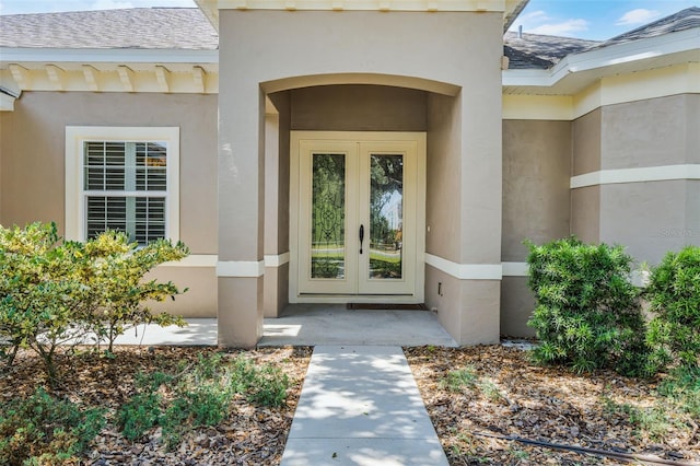 doorway to property featuring stucco siding, roof with shingles, and french doors
