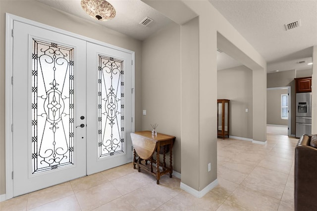 entrance foyer featuring light tile patterned floors, visible vents, and a textured ceiling