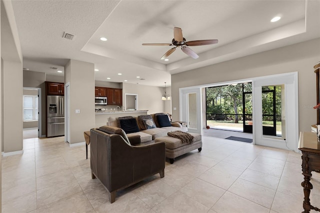 living room with recessed lighting, ceiling fan, a tray ceiling, visible vents, and plenty of natural light