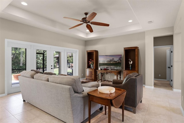 living room with baseboards, recessed lighting, a ceiling fan, and a tray ceiling