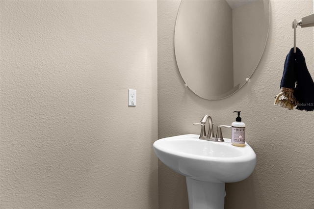 bathroom featuring a textured wall and a sink