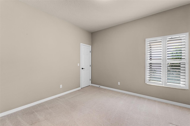 unfurnished room with light colored carpet and baseboards