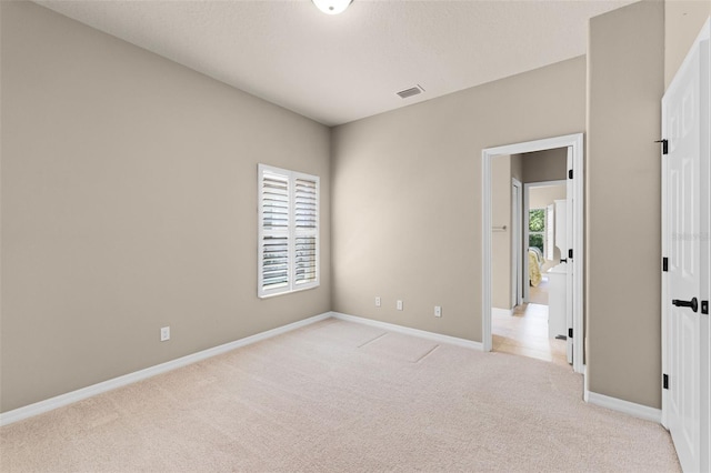empty room featuring baseboards, visible vents, and light colored carpet