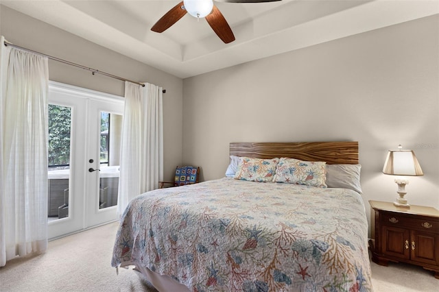 bedroom featuring a raised ceiling, ceiling fan, access to exterior, light carpet, and french doors