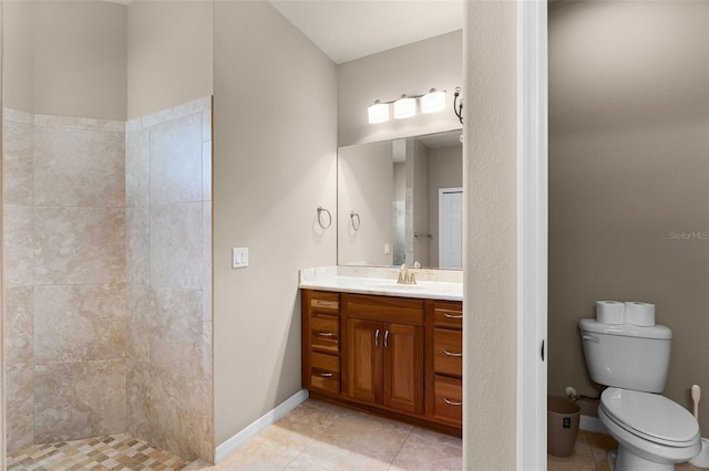 bathroom featuring baseboards, toilet, tile patterned floors, vanity, and tiled shower